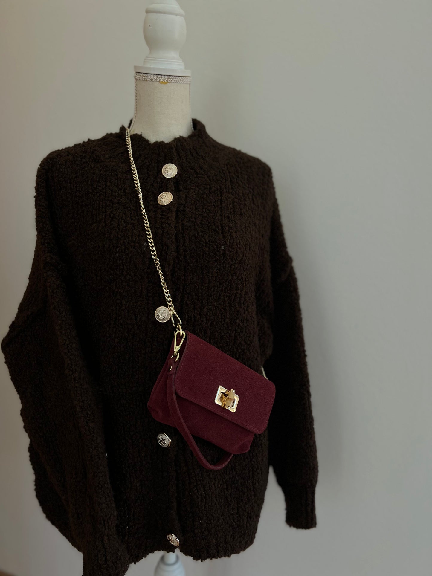 Dunkelbrauner Damen-Cardigan aus festerem Strickmaterial, klassisch geschnitten mit goldenen Knöpfen, eleganter und sportlicher Look. 
Dazu dunkelrote Handytasche aus Wildleder